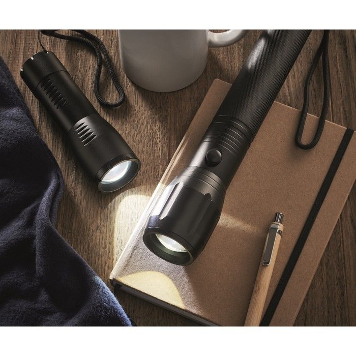 Taschenlampe schwarz in klein und großer Ausführung auf Schreibtisch.