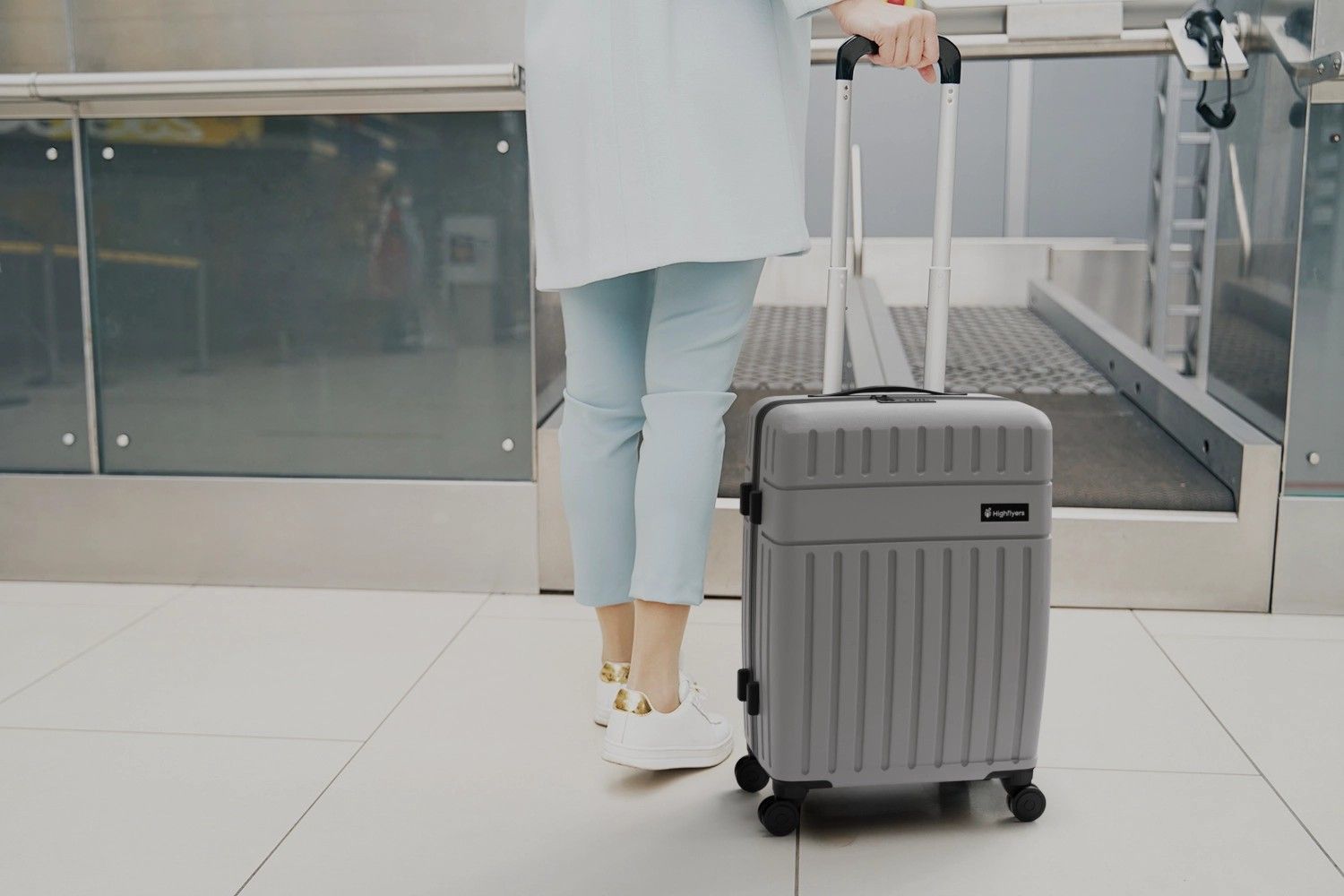 Person steht mit Trolley am Flughafen bei Gepäckabgabe