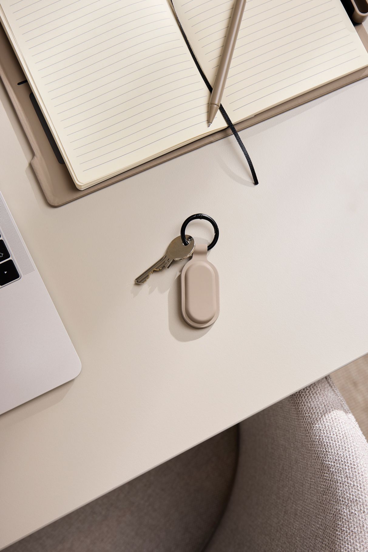 Ein Keyfinder bzw. Bluetooth-Tracker hängt an einem Schlüsselbund und liegt auf einem Schreibtisch.