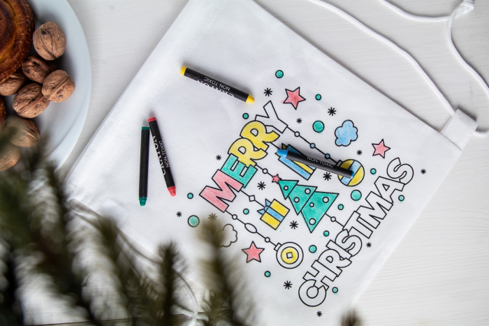 Eine weiße Tasche mit einem vorgedruckten Weihnachtsmotiv liegt bereit zum selbstausmalen.