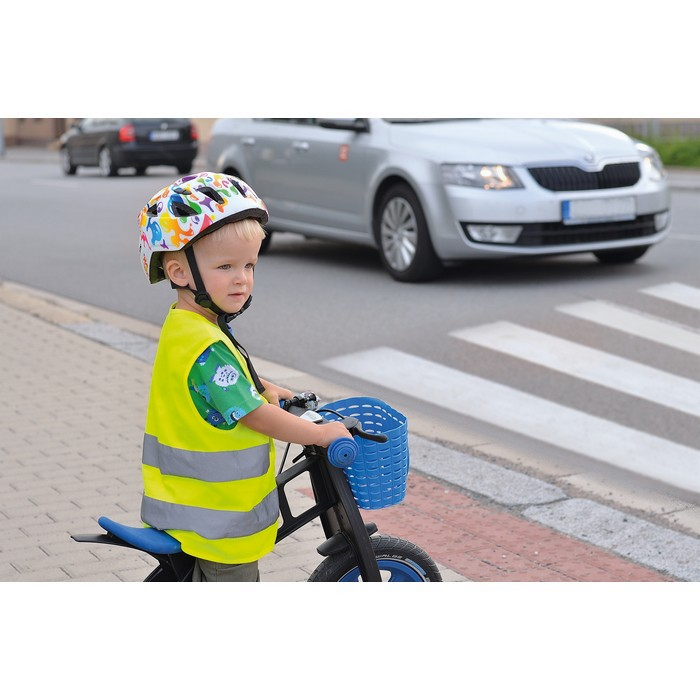 Ein kleines Kind steht mit seinem Fahrrad am Zebrastreifen und trägt eine Sicherheitsweste.