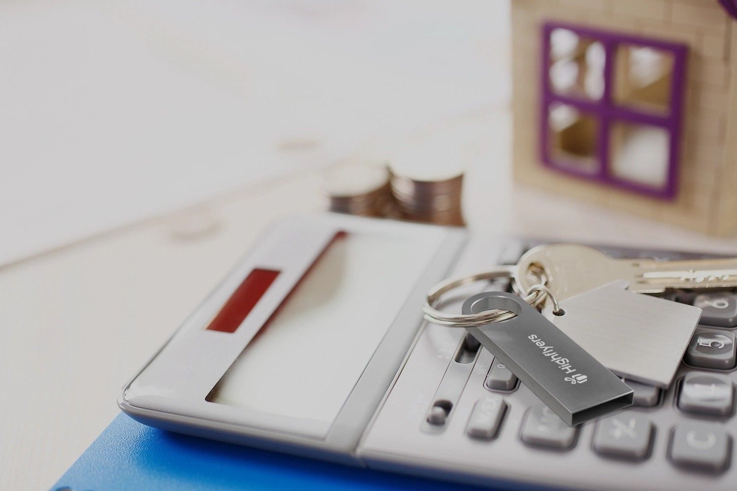 silberner USB Stick mit Logo lan einem Schlüsselbund auf Taschenrechner