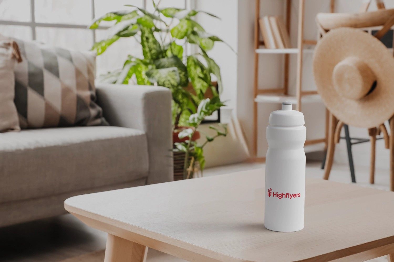 weiße Sportflasche mit Logo auf Wohnzimmertisch mit Couch im Hintergrund