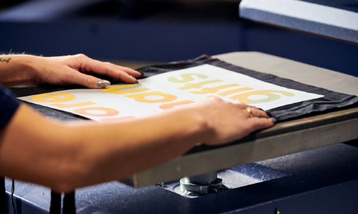 Das Motiv für einen Digitaltransferdruck wird auf einem schwarzen Stoffbeutel genau platziert.