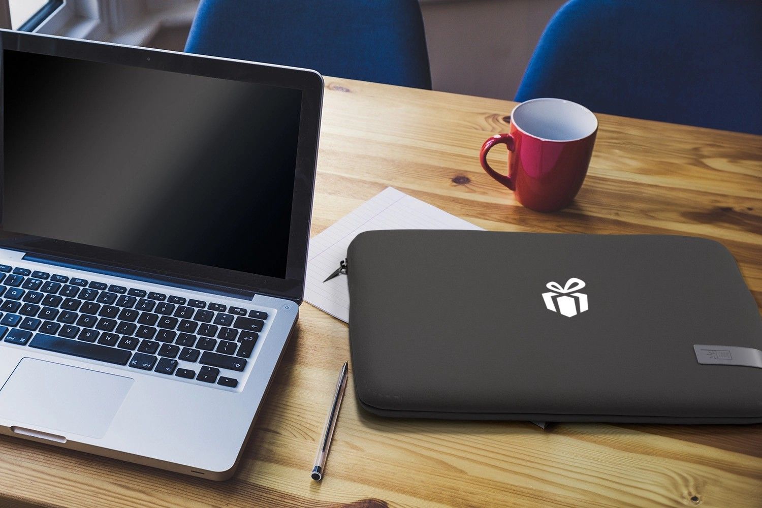 Laptoptasche mit Logo liegt auf Holztisch neben Laptop