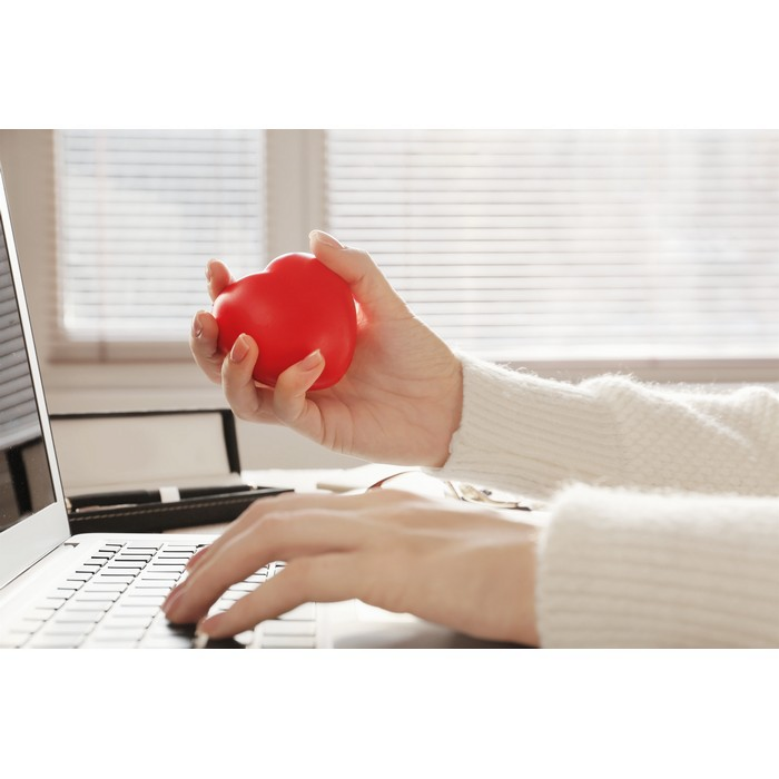 Ein Anti-Stress-Ball in Form eines Herz wird zusammengedrückt.
