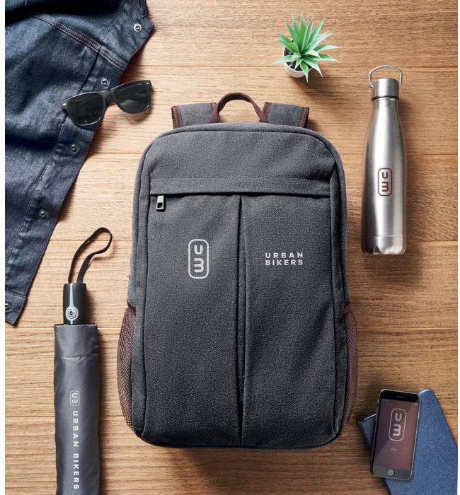 Auf einem Tisch liegt ein Rucksack mit  Isolierfalsche und Regenschirm. Alles ist mit Transferdruck veredelt.