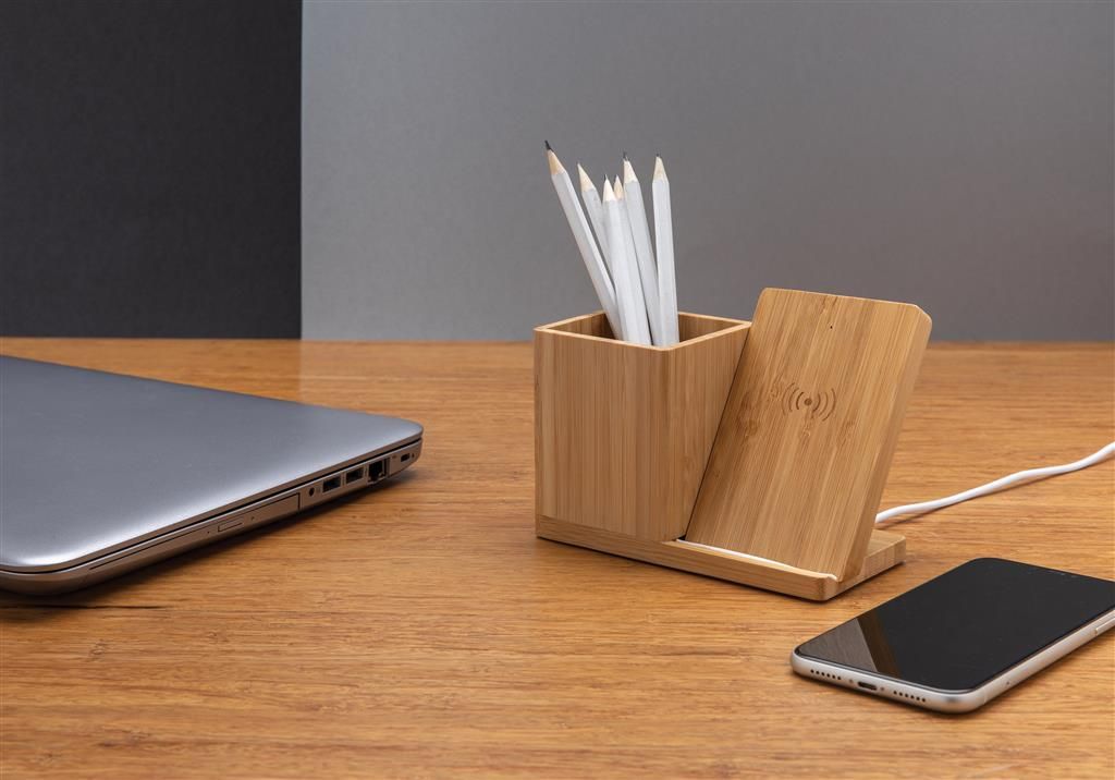 Stiftehalter mit Induktionsladegerät auf Schreibtisch neben Smartphone und Tablet.