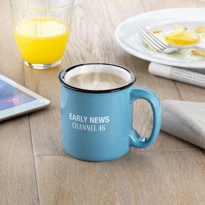 Eine blaue Keramiktasse steht auf einem Holztisch. Ein weißer Keramiktransferdruck ziert den schönen Becher.