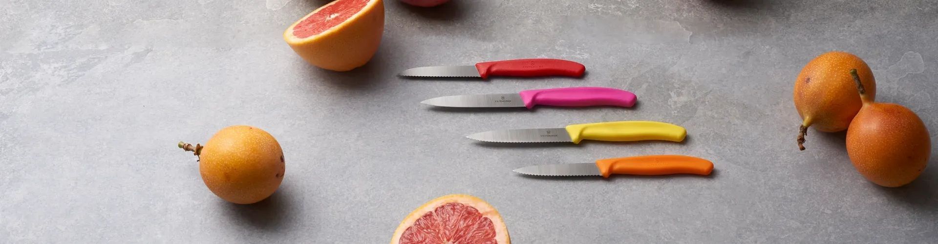 Verschiedene bunte Gemüsemesser von Victorinox werden auf einem Tisch präsentiert.