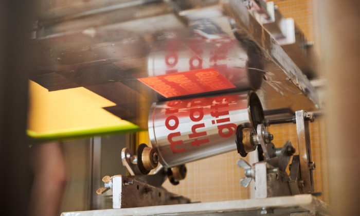 Eine moderne Siebdruckmaschine bedruckt einen Thermobecher mit einem roten Siebdruck rundum.