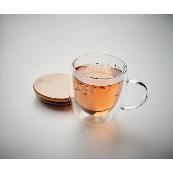 Eine Glastasse mit einem weihnachtlichen Aufdruck steht auf einem Tisch.