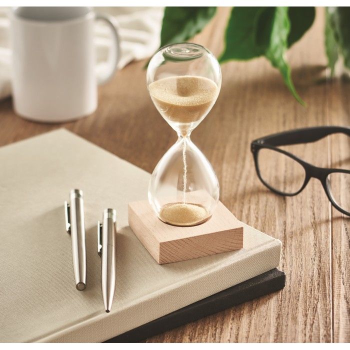 Sanduhr auf Schreibtisch  mit Stiften und Brille.